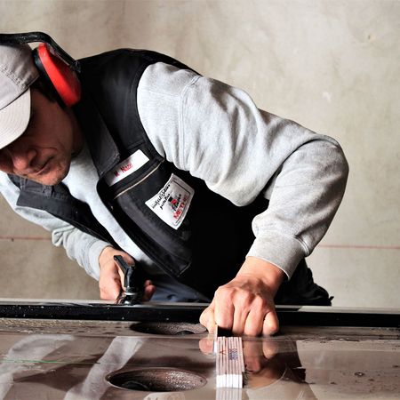 Ein Mann mit Ohrschützern bearbeitet eine Fliese