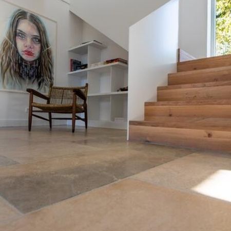 Gefliester Boden nahe einer Holztreppe eines Raumes mit einer Zeichnung einer Frau an der Wand