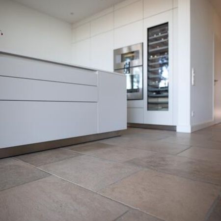 Gefliester Boden nahe dem Kochbereich mit weißer Anrichte als Raumteiler