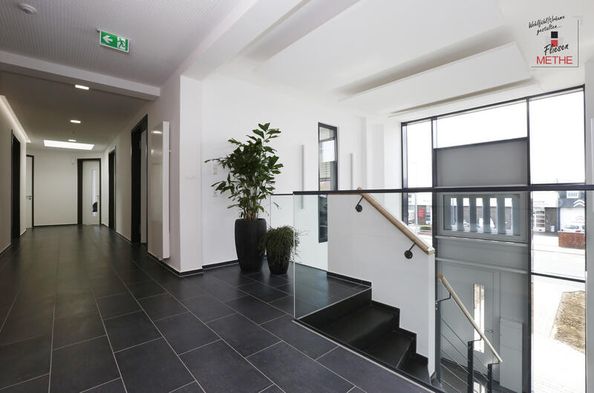 Weißer Eingangsbereich mit Treppe und dunklen Bodenfliesen