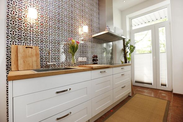 Hinter der Arbeitsfläche einer Küche sind gemusterte Fliesen angebracht